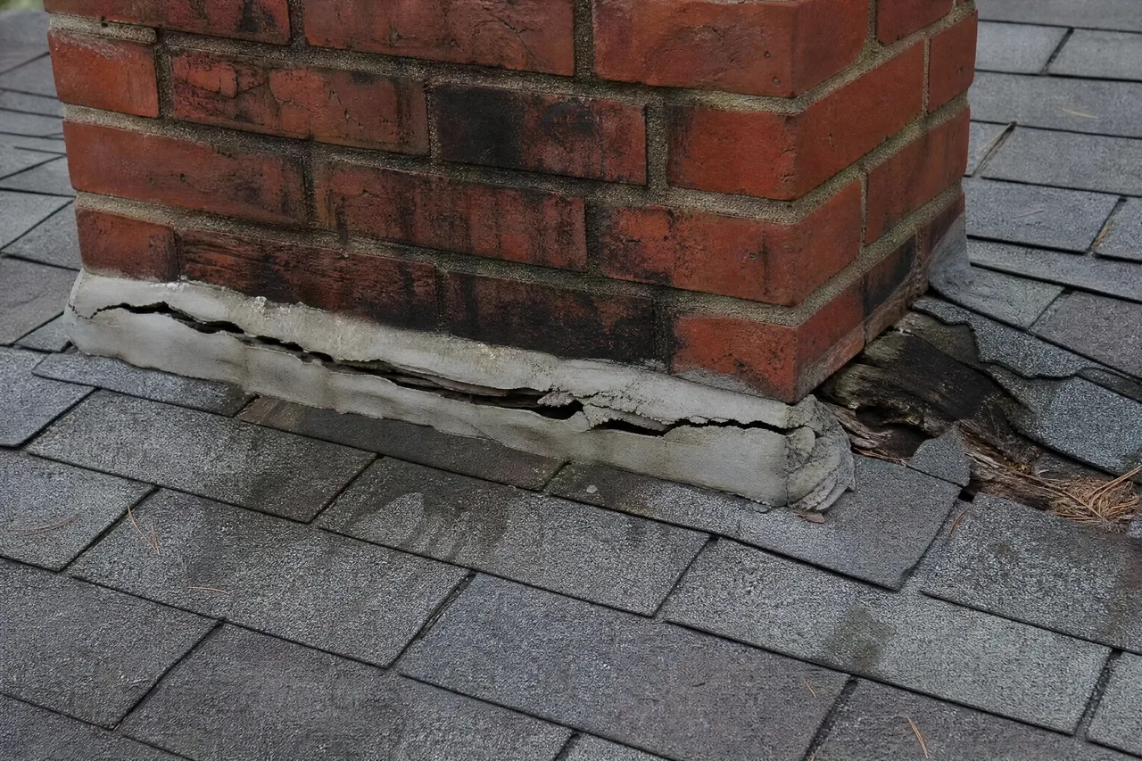 Failed chimney counterflashing and caulk repair on an Aurora IL roof before repair